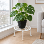 Base para maceta de hierro blanca con una monstera junto a una ventana
