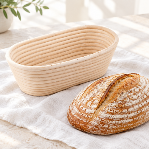 Canasta de ratán ovalada junto a un pan de masa madre con espirales marcadas