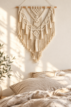 Tapiz de macramé color crema sobre una cama de lino con luz de mañana